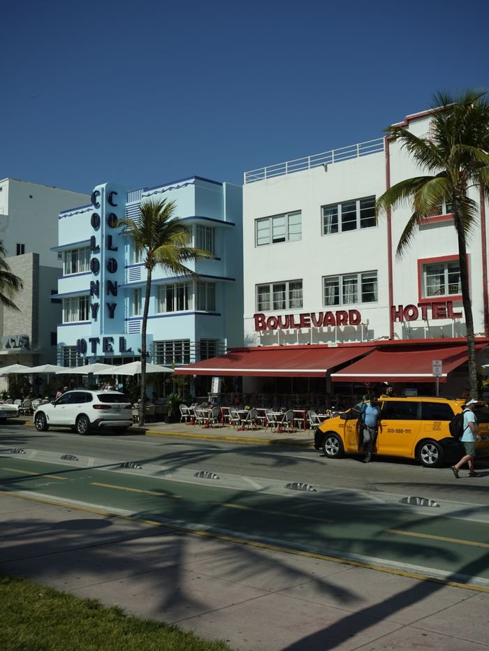 Vibrant Art Deco hotels and palm trees under clear skies on Miami Beach's iconic Ocean Drive.
